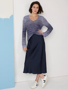 Dark navy blue midi slip skirt.  Model wears a blue ombre sweater and white sneakers.