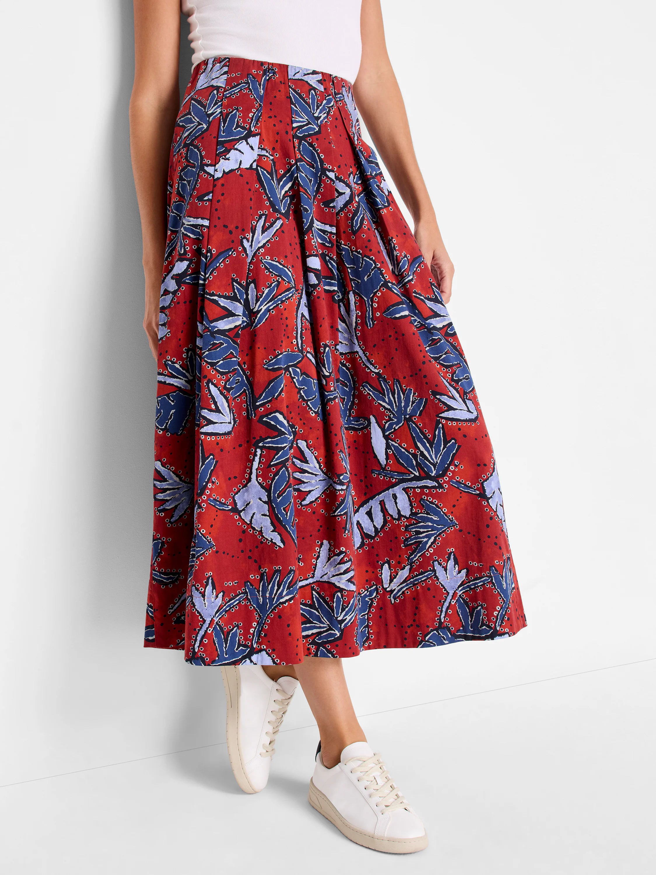 Midi pleated skirt; rust-red background with blue and purple leaf pattern.