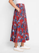 Red midi skirt with blue and purple leaf print, pleated, and side pockets.