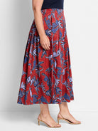 Red midi skirt with a pleated design. Features a blue and purple leaf pattern on a red background.