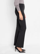 Black, bootcut pants shown on a model.  The pants have a mid-rise waist.