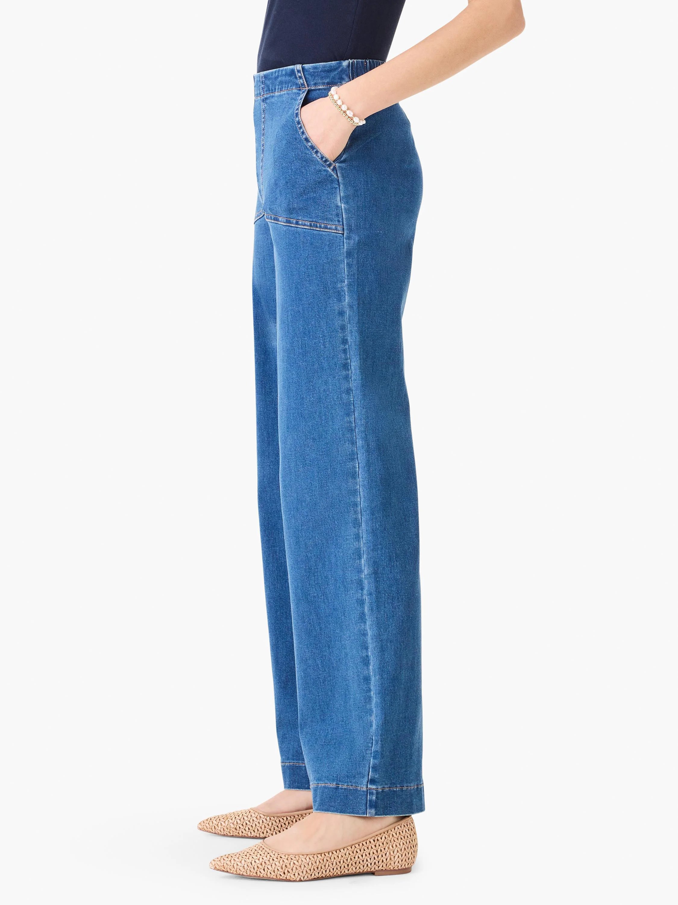 Medium blue wide leg denim jeans with front patch pockets, prominent vertical seams, and a cuffed hem.