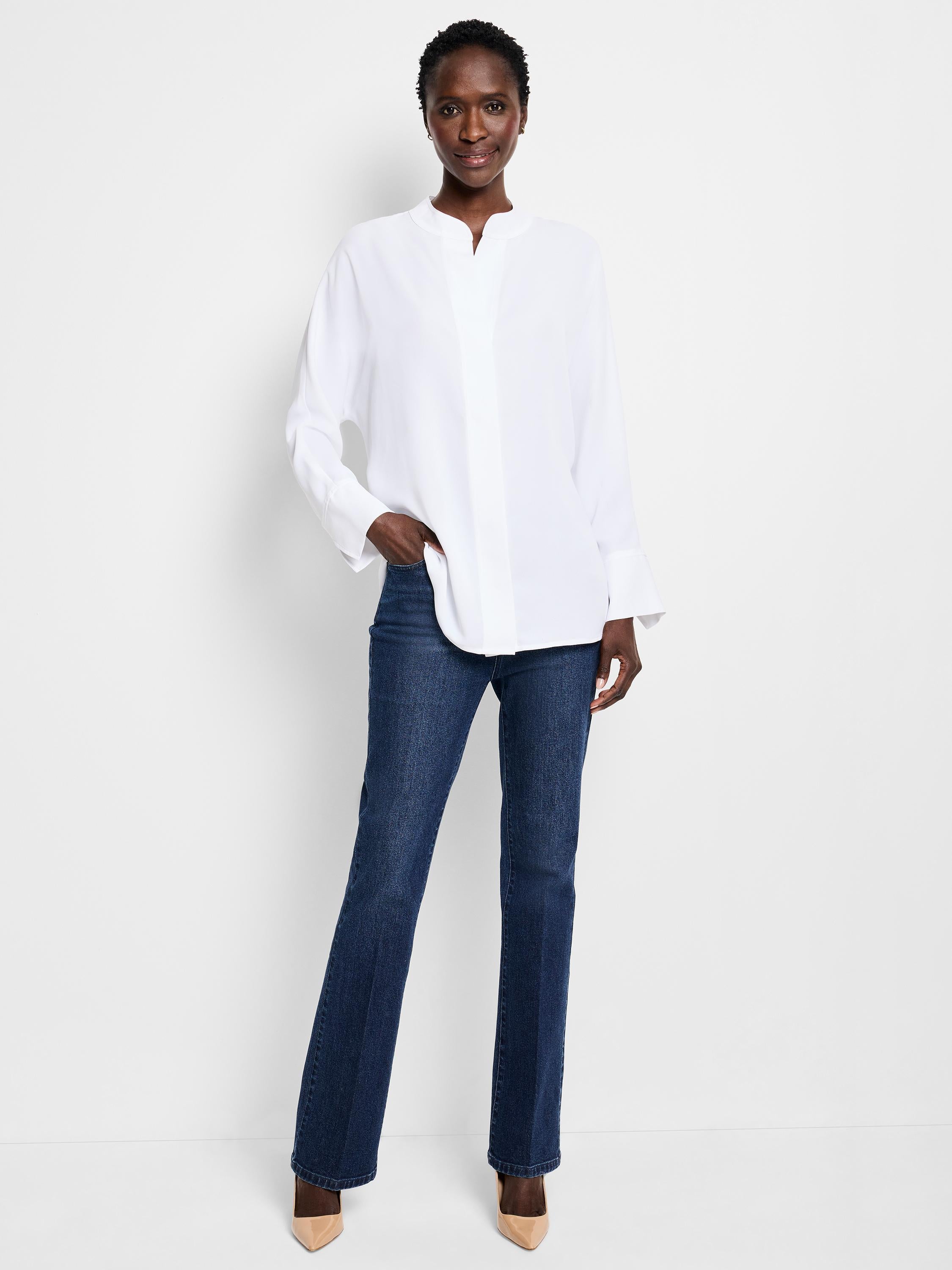 A woman wears a relaxed fit white band collar blouse paired with dark indigo straight leg jeans.