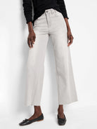 Light grey wide leg jeans, cropped above ankle, with a frayed raw hem. Button fly and front pockets visible.