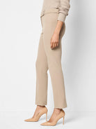 Beige straight-leg pants; cropped, buttoned waist.  Model wears nude heels.