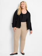 Beige straight-leg pants on a model.  The pants are a light beige.  A black jacket is also visible.