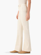 High-waisted ecru bootcut jeans with visible side panels and a flared hem.