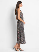 Black midi dress with multicolored spotted pattern; sleeveless, pleated skirt.