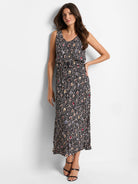 Black sleeveless midi dress with multicolored spotted pattern and belted waist. Pleated skirt.