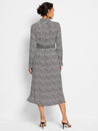 Off-white midi dress with dark-navy spots, long sleeves, collared neckline, and a belted waist.