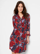 Rust-red long-sleeve dress with navy and lavender leaf pattern. Features a shirt collar and above-knee length.