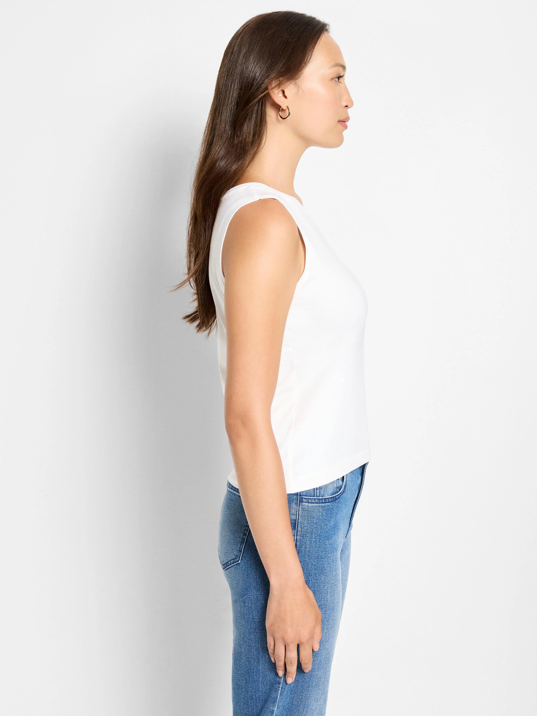 White knit tank, sleeveless with a round neck, shown on a model in profile.