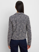 Back view of a dark blue and cream cropped knit jacket with a woven checkered pattern.