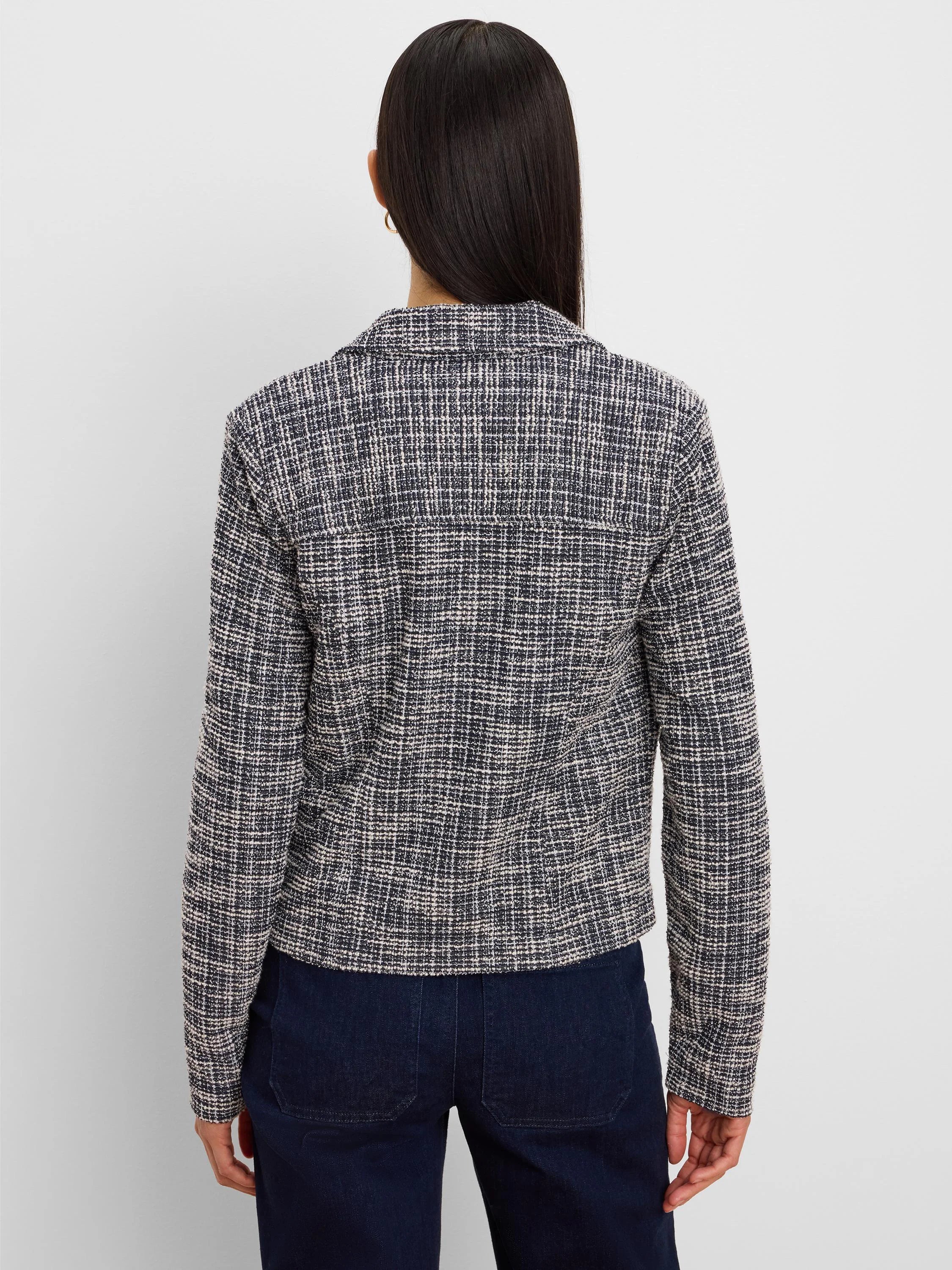 Back view of a dark blue and cream cropped knit jacket with a woven checkered pattern.