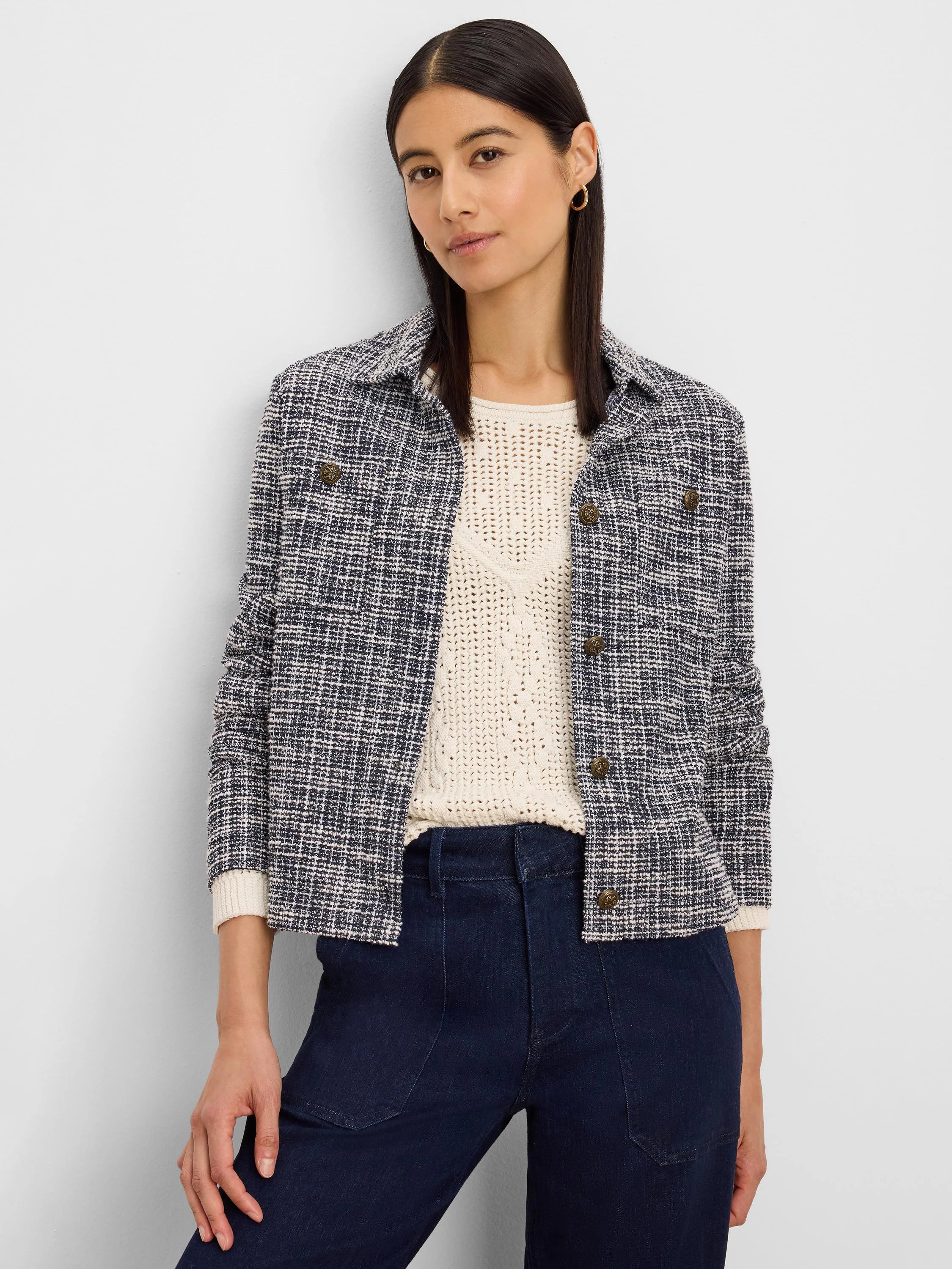 Cropped knit jacket with dark blue and cream interwoven texture. Features a collar, long sleeves, and gold buttons on...