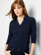 Navy ribbed knit polo with collar, V-neck, long sleeves, and a white button placket.