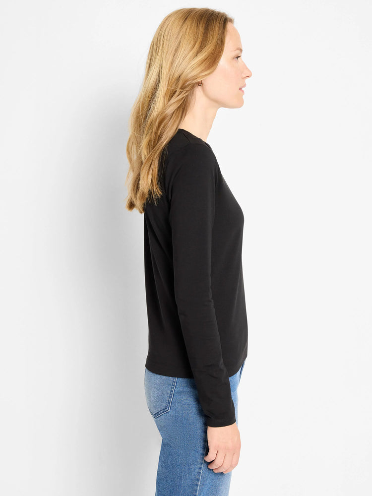 Black long-sleeve knit top on model. Smooth texture, rounded neckline, and a gentle, fitted shape.