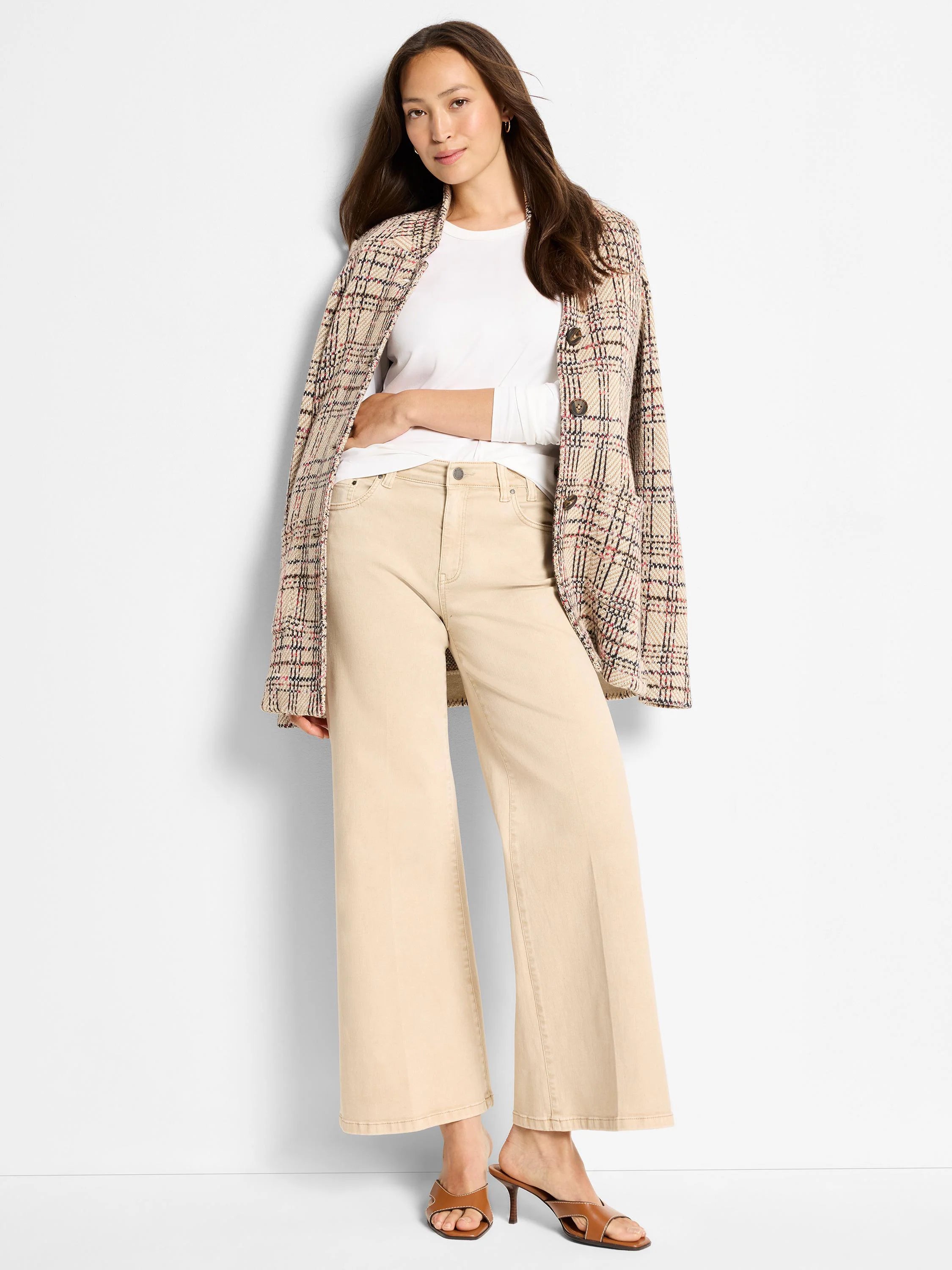 White, round-neck, long-sleeve knit top worn by a model, partially covered by a plaid jacket and beige pants.