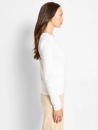 White, smooth, round-neck long sleeve top on a model in profile.