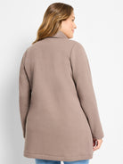 Light brown, tunic-length jacket with a stand collar and long sleeves, modeled by a woman facing right.