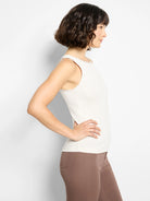 Light cream ribbed tank top with a high neckline and trimmed edges, modeled from the side.