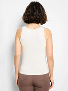 Back of a light cream ribbed knit tank top, shown on a model. Features a rounded neckline with subtle trim.