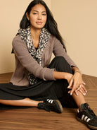 Taupe moto jacket with a smooth body and ribbed knit sleeves, featuring a zippered front.