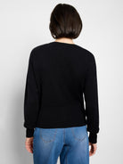 Back view of a black pure cotton cardigan. It features a fine knit body with ribbed cuffs and hem.