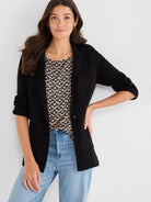 Black knit blazer with notched lapels, a single button, and pushed-up three-quarter sleeves.
