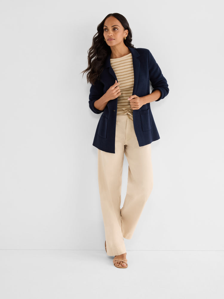 A model wears a relaxed navy knit cardigan blazer featuring patch pockets over beige wide-leg pants.
