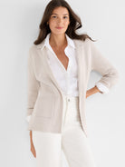 Relaxed oatmeal knit blazer with lapels and patch pockets worn open over a white shirt.