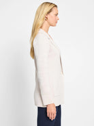 Light beige knit blazer with notched lapels, single button, and patch pockets. Worn by a model in profile.