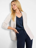 Light beige knit blazer with lapels, open front, two patch pockets, and a single cream button.