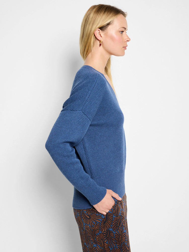 Medium blue V-neck sweater with a subtle tuck stitch texture and ribbed cuffs and hem.