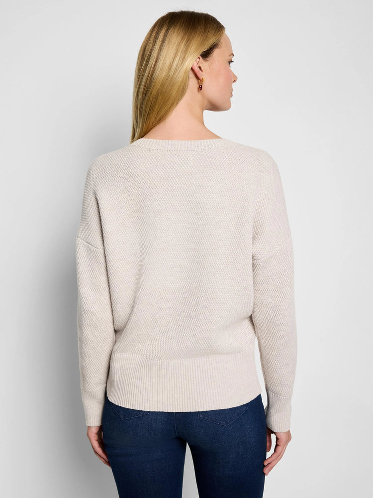 Oatmeal tuck stitch sweater, back view, with a round neck, dropped shoulders, and ribbed cuffs/hem.