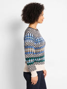 Multi-color knit sweater with black, white, blue, green, and tan geometric patterns featuring zigzags and vertical bars.