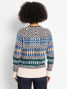 Graphic sweater: black, off-white, blue, tan, green geometric stripes. Off-white ribbed hem and cuffs.