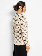 Cream sweater with black geometric linked pattern of rounded diamonds and black ribbed trim.