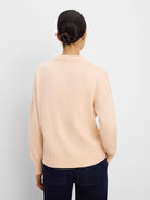 Light peach cotton cashmere sweater, back view, with ribbed neck, cuffs, and hem, loose fit.
