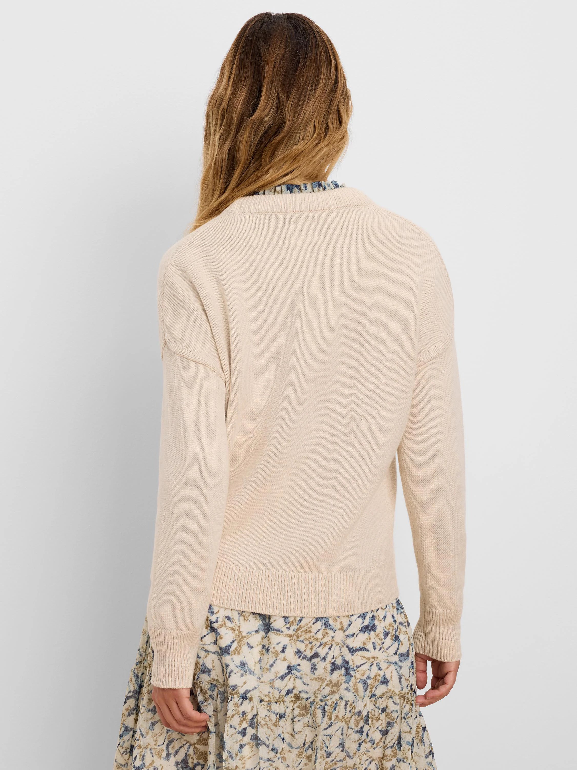 Light beige cotton cashmere sweater, back view. Shows knit texture, ribbed cuffs, hem, and back collar.