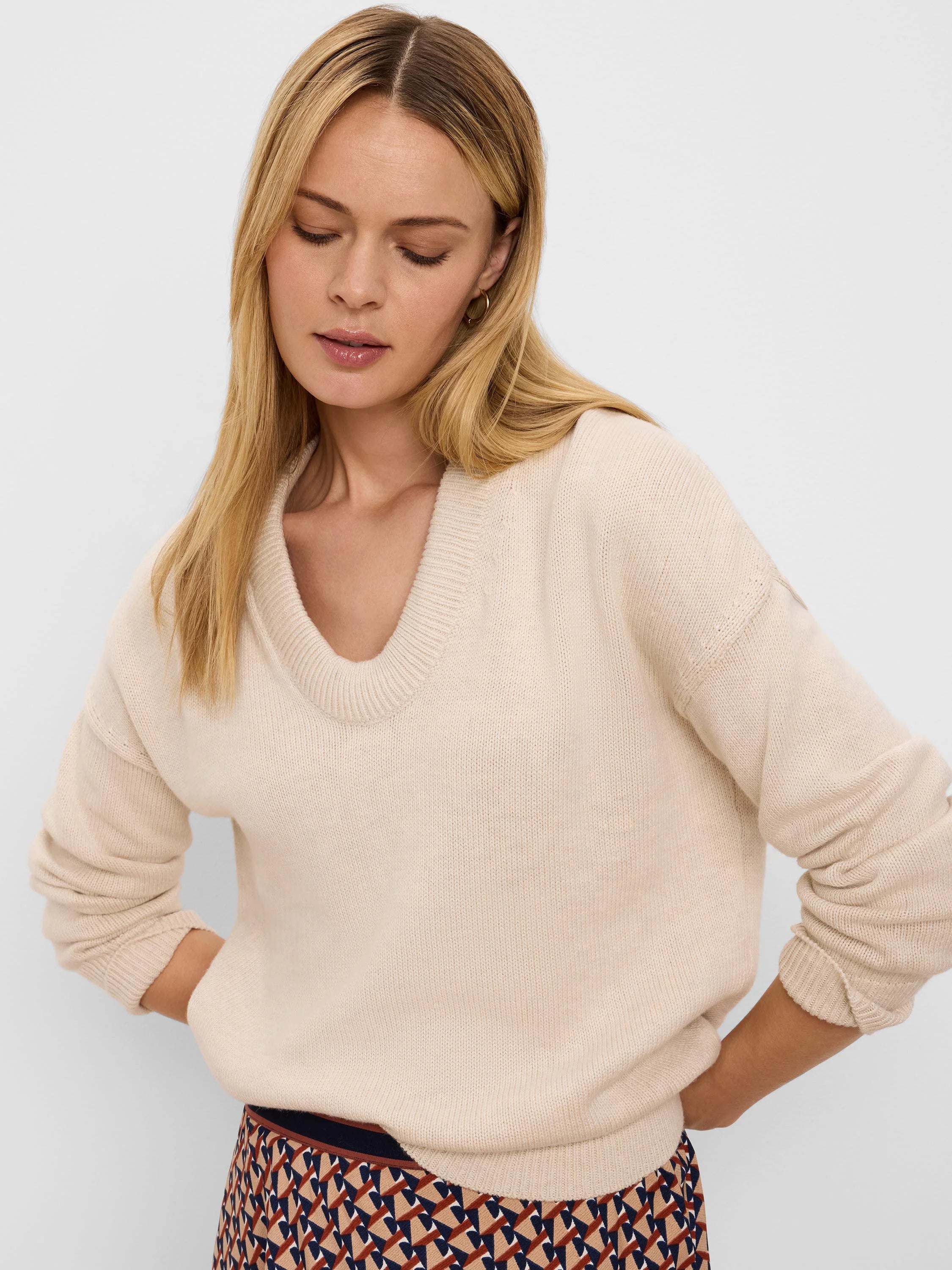 Cream scoop neck sweater with a relaxed fit, dropped shoulders, and long cuffed sleeves.