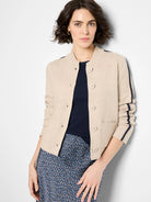 Light beige knit bomber jacket with ribbed collar, button front, navy zigzag sleeve details, and front pockets.