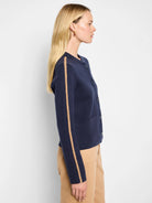 Navy knit bomber jacket with a round neck, front buttons, pockets, and a tan zig-zag stripe down each sleeve.