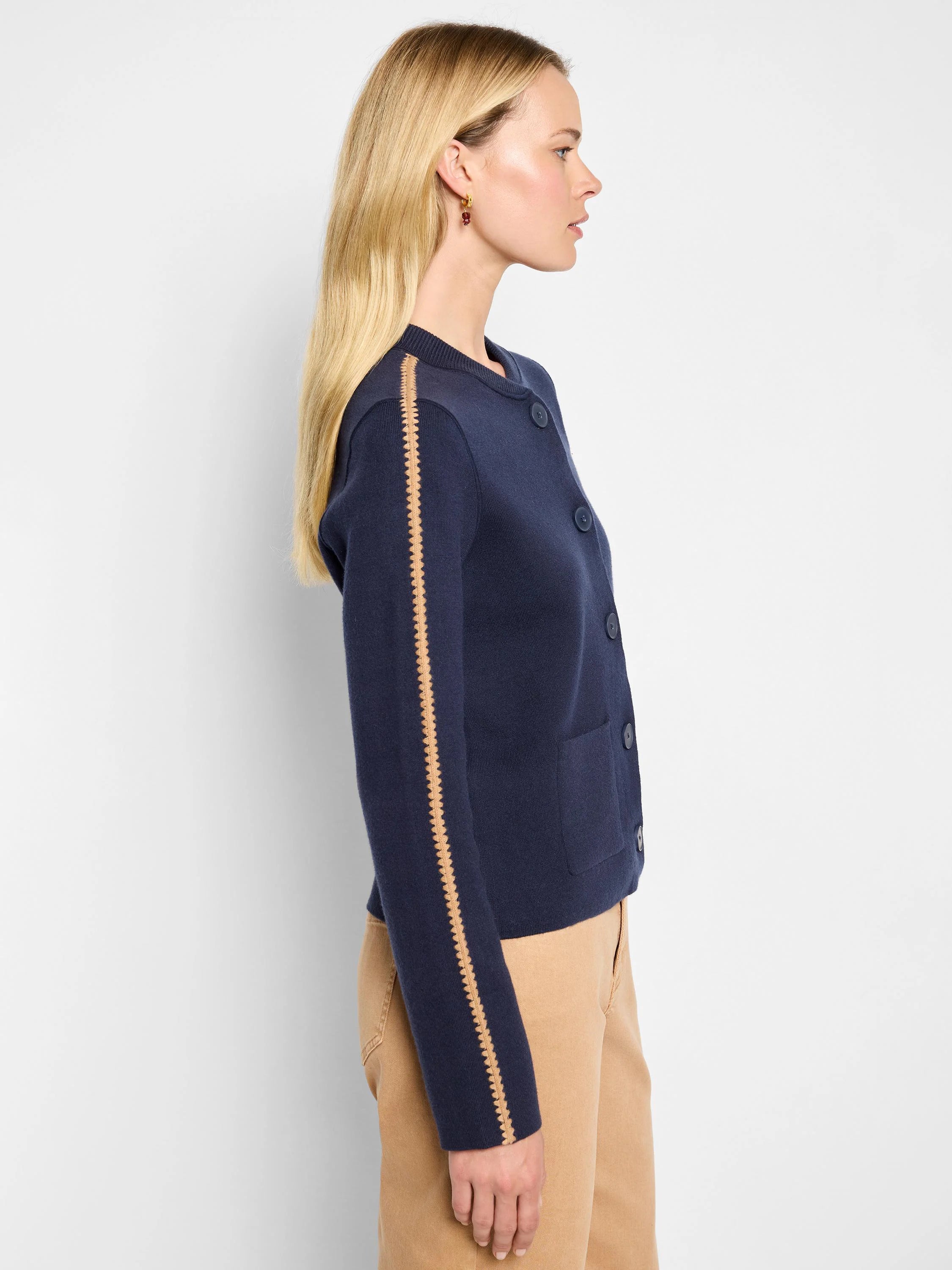 Navy knit bomber jacket with a round neck, front buttons, pockets, and a tan zig-zag stripe down each sleeve.