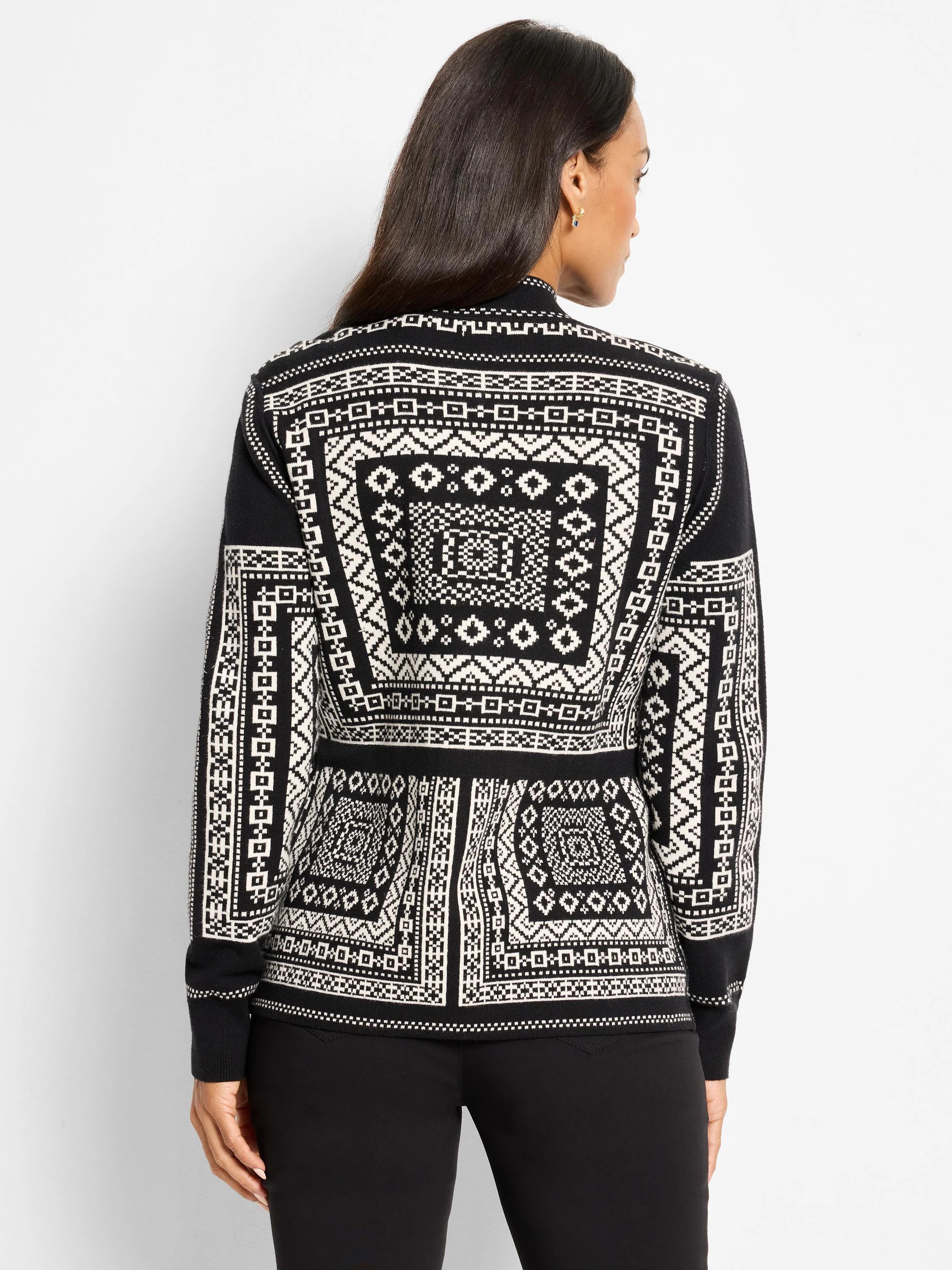 Black and white knit jacket with intricate geometric Nordic pattern covering the back and sleeves, worn from behind.