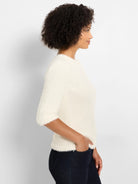 Creamy white fuzzy sweater with a round neck and 3/4 sleeves.