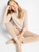 Light beige mock-neck sweater with a subtle pixel knit texture and long sleeves.