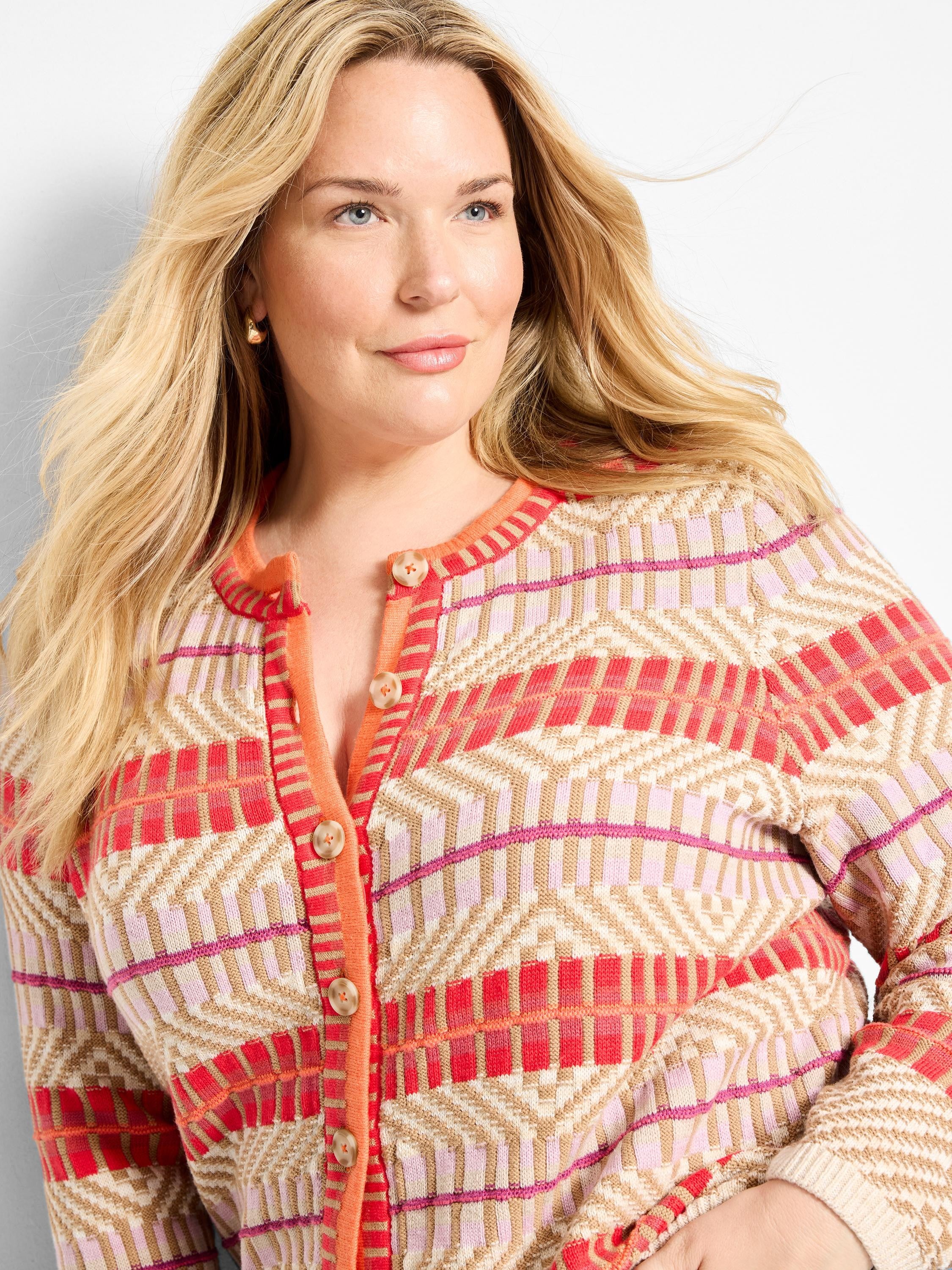 Tan, pink, and red geometric pattern button-front cardigan with a solid coral placket and buttons.