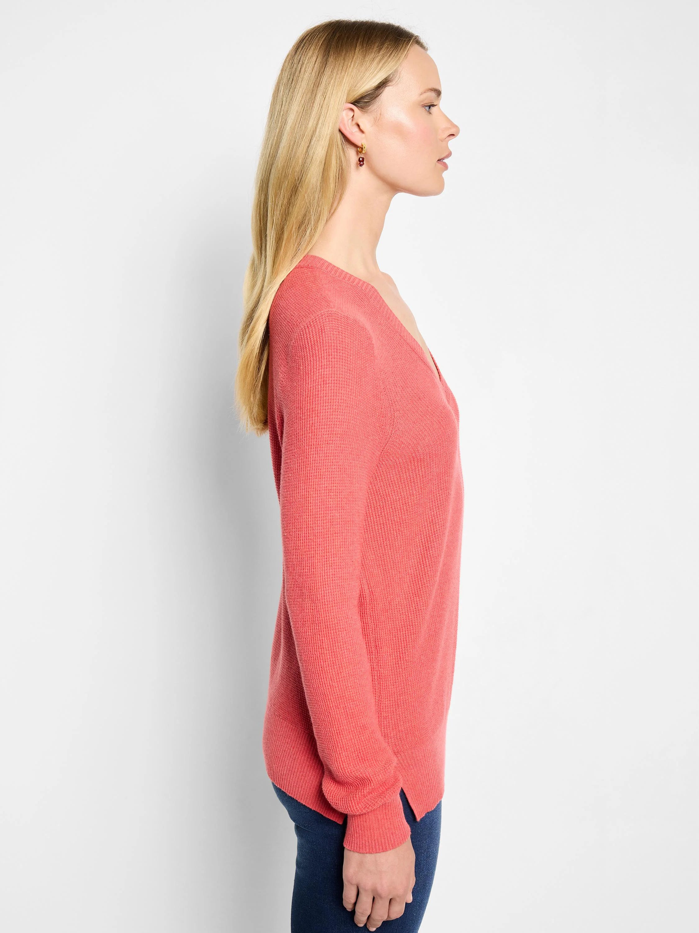 Coral pink waffle stitch V-neck sweater. Features a relaxed fit, long sleeves, and side slits.