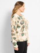 Tan sweater with green/brown abstract shapes, scattered white sequins. Round neck, ribbed cuffs.